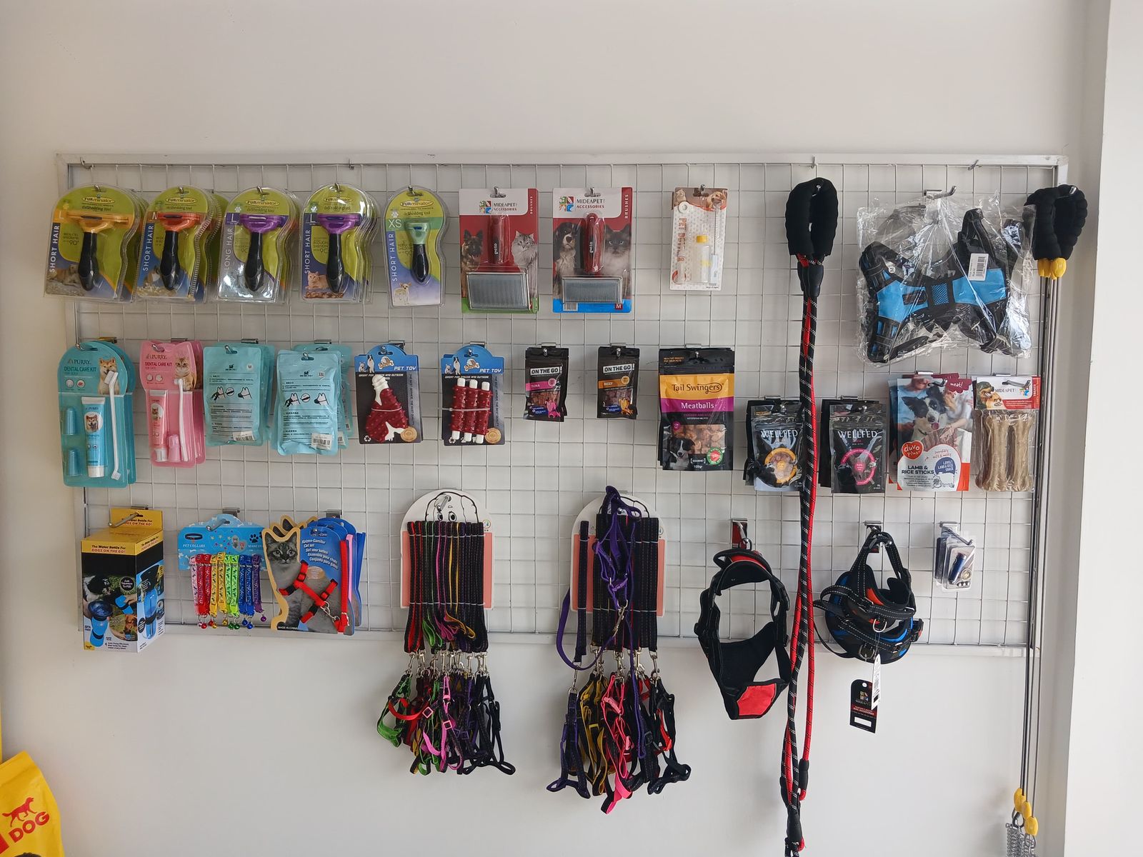 Wall of pet accessories in the Farmavet shop — leashes, harnesses, grooming tools and treats