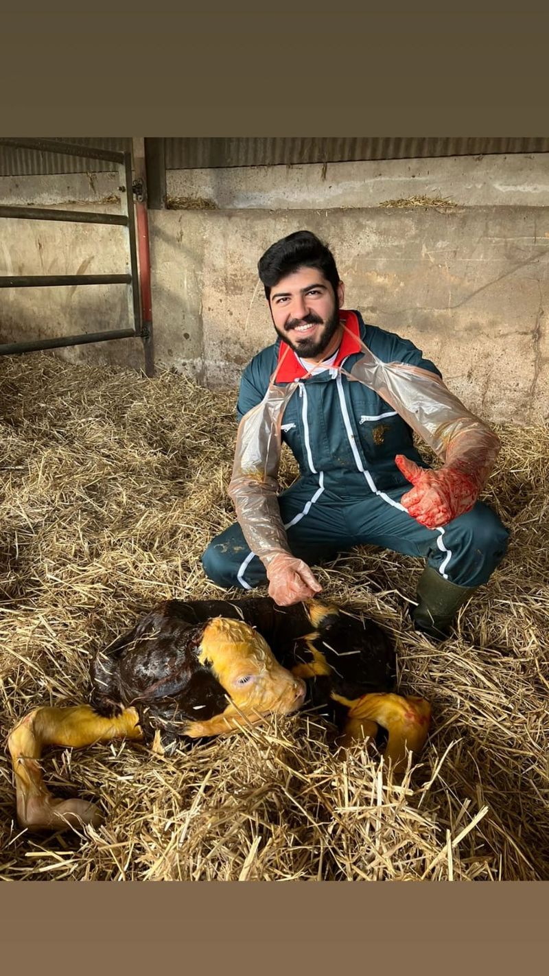Dr Joseph giving a thumbs up beside a newborn calf